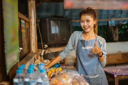 female stall keeper shows thumbs up while setting the table of a traditional stallの写真素材