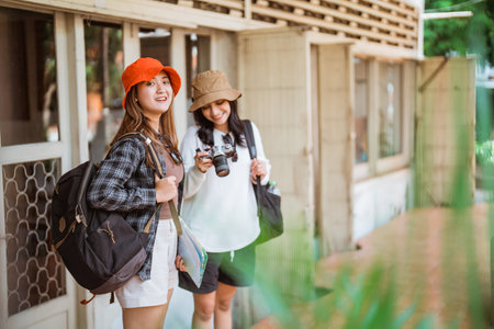 two smiling local tourists carrying a camera stand in front of the houseの写真素材