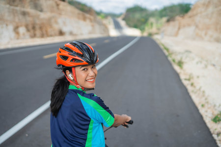 cheerful female cyclist smiling when riding bike, rear viewの写真素材