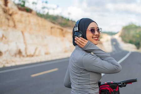 hijab woman wearing earphone when riding bike, rear view, biking conceptの写真素材