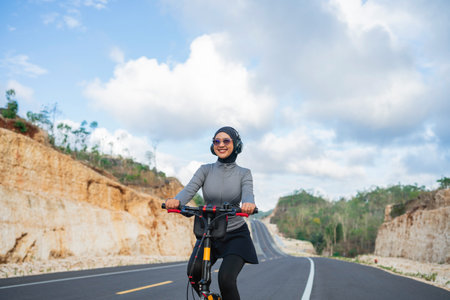 hijab biker wearing earphone when biking on the roadの写真素材
