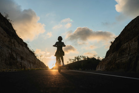 silhouette hijab woman riding bike during sunset, on the road, biking conceptの写真素材