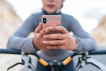 close up female biker hand holding phone, riding bike conceptの写真素材