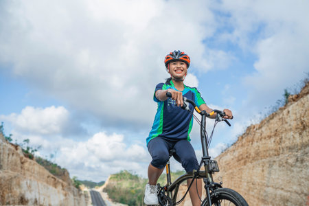 woman biker wearing helmet, enjoying riding bicycle outdoors, low angle viewの写真素材