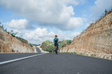female biker enjoying riding bike uphill, leisure and healthy activity, biking conceptの写真素材