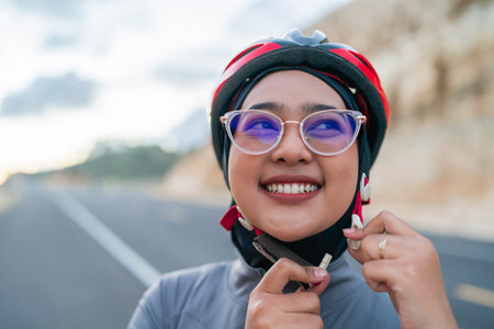 hijab biker putting on helmet for safety riding bike, close up shotの写真素材