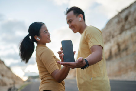 romantic runner couple wearing sportswear looking at each other while holding phoneの写真素材