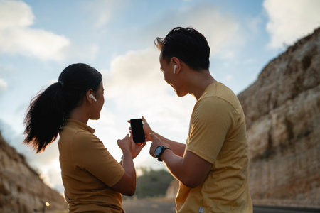 runner couple wearing sportswear using phone and earphone with pointing gestureの写真素材