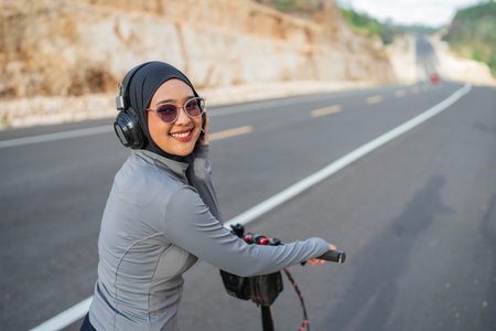 hijab biker listening to music using earphone, biking concept