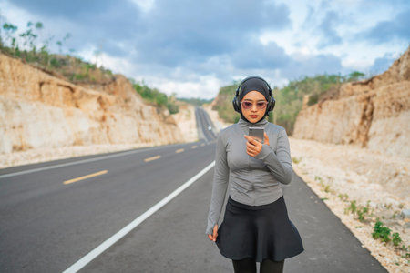 hijab woman wearing sportswear using phone and earphone during exercise in outdoor