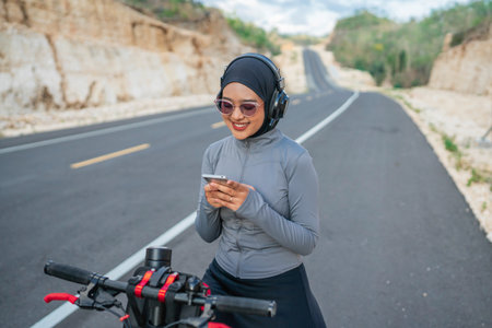 hijab biker using phone when riding bike, biking conceptの写真素材