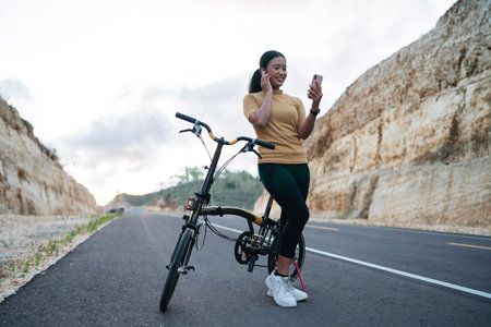 female biker using phone and earphone when biking on the road