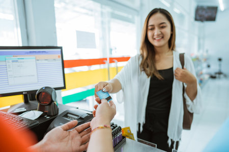 customer gives credit card to shopkeeper for payment while at minimarket cashierの写真素材