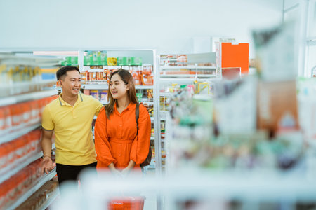 young couple shopping, young man and young woman chatting while shopping at the supermarketの写真素材