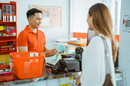 male shopkeeper holds goods for barcode scan of female customer shopping at minimarket cashier