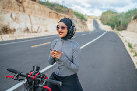 female athlete using phone when riding bike, biking conceptの写真素材
