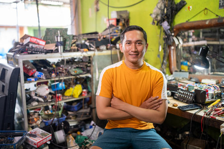 Asian Repairman sitting with his arms crossed in a service shopの写真素材