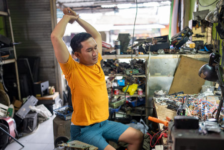 Asian male technician stretches after a long day at the service station