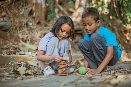 village boy and girls stacking piece of rooftile when playing traditional games
