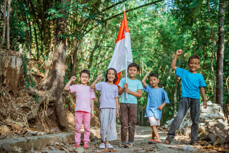 group of kids standing holding indonesian flag with raising fistの写真素材