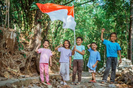 indonesian kids waving national flag and raising their hand to celebrate independence dayの写真素材