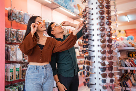 attractive woman and handsome Asian man wearing glasses while shopping at an accessories storeの写真素材