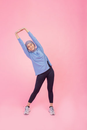 A woman wearing activewear is joyfully stretching her body in a vibrant and lively settingの写真素材