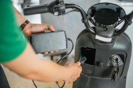 close up view of asian man hand taking off electric bicycle charger