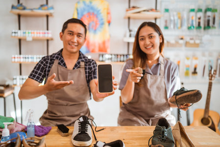 shoes cleaning worker holding mockup screen phone with pointing gestureの写真素材