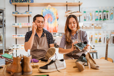 male worker holding phone, getting phone call while working at shoes cleaning studio