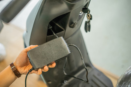 close up view of plugging in electric motorcycle charger at charging station