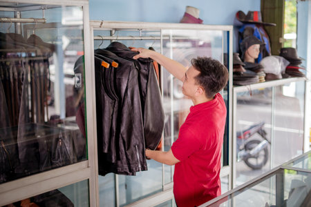 professional male entrepreneur in red polo shirt hanging leather jacket on shelfの写真素材