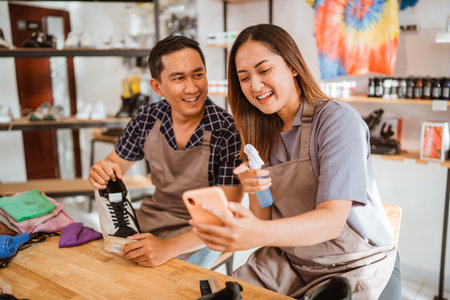 female employee holding phone and watching it with coworkerの写真素材