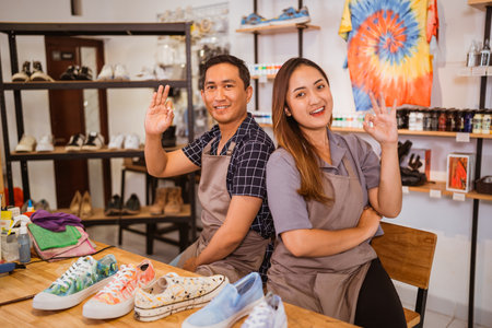 two Asian shoes painter sitting with okay hand gestureの写真素材