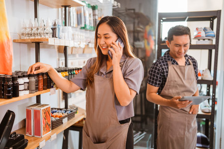 female staff getting phone call while checking product on shelf