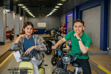 happy asian couple posing while riding electric bicycle at dealer store