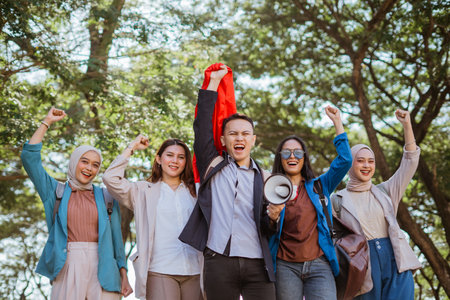 patriotic students with raised fist celebrate independence day and holding indonesian flag and megaphoneの写真素材