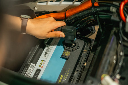 A hand skillfully connecting a connector to the battery pack of an electric vehicle