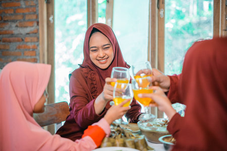 Muslim mother and Asian family break fast with a glass toast together at the dinner tableの写真素材