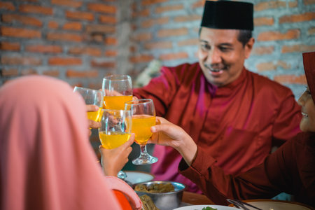 selective image focus Asian family breaking fast with glass toasts when together at the dining tableの写真素材
