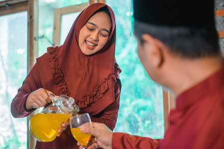 selective focus of a Muslim woman pouring drinks for husband when breaking the fast at home
