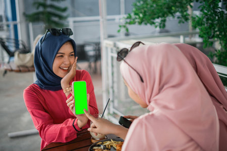 In a relaxed cafe, two smiling women are enjoying their time together with a smartphone