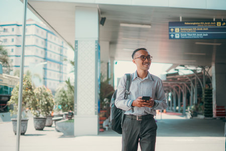 A confident man checks his phone while strolling through a vibrant city, enjoying the sightsの写真素材