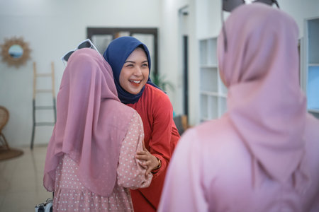Three close friends greet each other joyfully in a stylish, warm, and inviting indoor spaceの写真素材