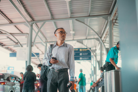 A businessman is using a smartphone while skillfully navigating the busy airportの写真素材
