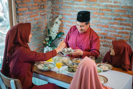 A family gathers around the table enjoying a traditional meal, highlighting their unityの写真素材