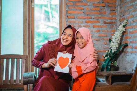 A joyful mother and her daughter express their profound love for one another using a heart symbolの写真素材
