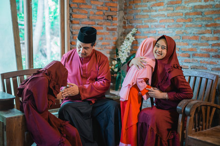 mom and dad shake hands and hug their two little daughters during the Eid celebration at home