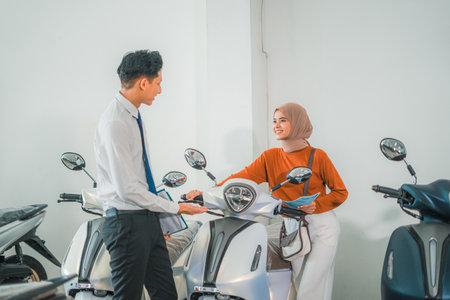 a female customer chooses a new motorcycle with a male salesperson at a motorcycle showroomの写真素材