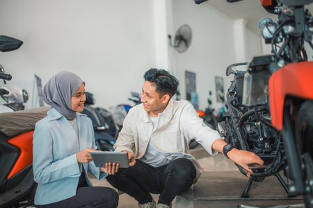 handsome Asian man check out a new motorcycle with a saleswoman with a tablet in a showroomの写真素材